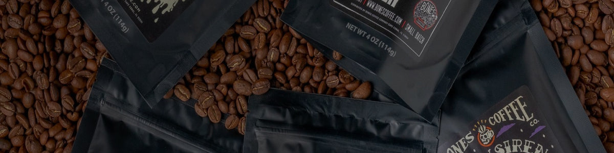 Five four ounce bags of coffee are on top of coffee beans.